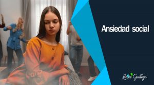 Joven con expresión triste y preocupada sentada en un sofá, mientras al fondo otras personas interactúan y bailan, reflejando el sentimiento de ansiedad social y aislamiento en un entorno de grupo